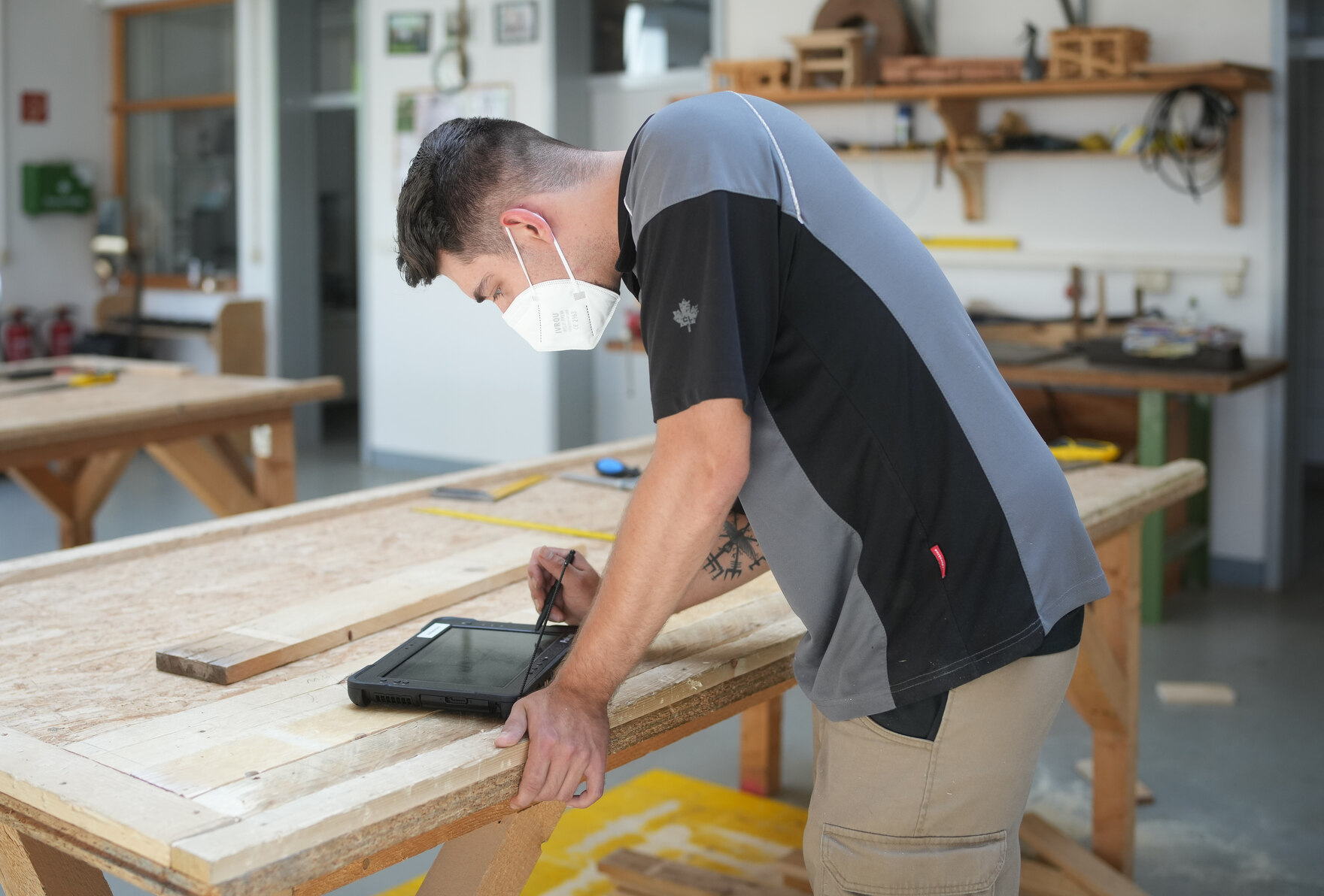 Ein Auszubildender bedient an der Werkbank ein Tablet.