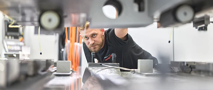 Ein Mitarbeiter beim Unternehmen Starrag schaut in eine Maschine.